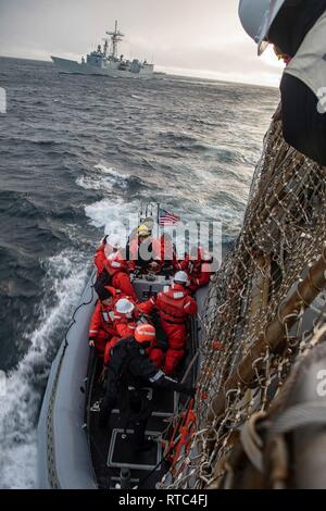 Norwegische See (Feb. 8, 2019) Standing NATO Maritime Group 1 (Snmg) Personal komplette Verpflegung eine starre - Rumpf Schlauchboot aus der geführten Anti-raketen-Zerstörer USS Schwer (DDG107), die Snmg 1 Flaggschiff, vor ihrer Übertragung an die Polnische marine Fregatte ORP General Kazimierz Pulaski (FrR 272). Schwerwiegend ist unterwegs auf einem regelmäßigen Einsatz als Flaggschiff der SNMG 1 Operationen durchzuführen und eine kontinuierliche maritime Fähigkeit zur NATO im nördlichen Atlantik. Stockfoto