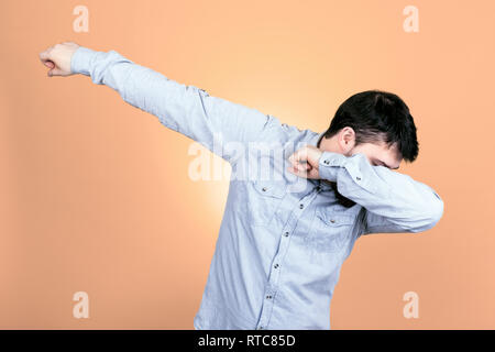 Anonyme Mann im Hemd in DAB-dance Pose auf pastellorange Hintergrund Stockfoto
