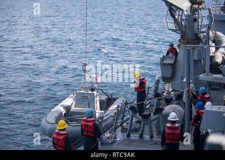 U.S. Navy Sailors arbeiten zusammen, um zu einem starren hull Inflatable Boat Launch an Bord der geführte Anti-raketen-Zerstörer USS Stockdale (DDG106) im Arabischen Meer, Feb 11, 2019. Die Stockdale ist in die USA 5 Flotte Bereich der Maßnahmen zur Unterstützung der Marine im Einsatz für die Stabilität und Sicherheit in der Region zu gewährleisten und verbindet das Mittelmeer und den Pazifischen Raum durch den westlichen Indischen Ozean und drei strategischen Punkten ersticken. Stockfoto