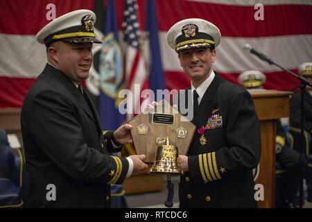 Die SOUDA BUCHT, GRIECHENLAND, 14.02.2019 - U.S. Navy Capt. Todd Marzano, kommandierender Offizier, San Antonio-Klasse amphibious Transport dock Schiff USS Arlington LPD (24), ist mit einem Geschenk von den Offizieren der Arlington an seinem Wechsel der Befehl Zeremonie, Feb 14, 2019 präsentiert. Die USS Arlington einen geplanten Einsatz als Teil der 22 MEU und der kearsarge Amphibischen bereit, zur Unterstützung der Maritime Security Operations, Krisenbewältigung und Theater Zusammenarbeit im Bereich Sicherheit und zugleich eine vorwärts Naval und Marine Präsenz. Stockfoto