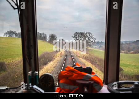 Blick auf das Cockpit des Dieseltriebfahrers durch das Kabinenfenster des fahrenden Zuges auf der historischen Linie der Severn Valley Railway, die durch die ländliche Landschaft Großbritanniens führt. Stockfoto