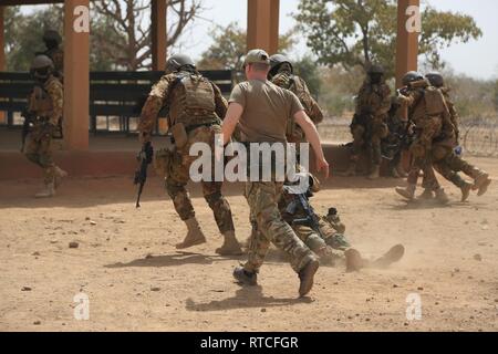 Eine tschechische Special Forces Soldat beobachtet Malischen Soldaten, wie sie einen Unfall während einer medizinischen Ausbildung Demonstration in Loumbila, Burkina Faso Feb.16, 2019, zu decken während Flintlock 2019 bewegen. Das Training vermittelt Malischen Soldaten die Gelegenheit, praktische medizinische Erfahrung von multinationalen Special forces Soldaten zu erhalten. Stockfoto