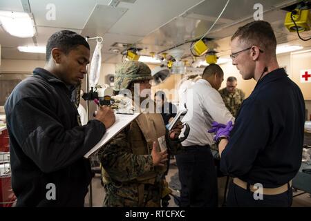 Golf von Thailand (Feb. 16, 2019) - Lt Gloria Oakman, 3. Medizinischen Bataillon zugeordnet, beschreibt Verletzungen eines simulierten Patienten in den Operationssaal des amphibious Transport dock Schiff USS Green Bay LPD (20) Während ein Unfall Evakuierungsübung. Green Bay, Teil der Wasp amphibischen bereit, Gruppe, mit Eingeschifft 31 Marine Expeditionary Unit (MEU), in Thailand, die in der Übung Cobra Gold 2019 zu beteiligen. Cobra Gold ist eine multinationale Übung von Thailand und den Vereinigten Staaten gefördert werden, ist entworfen, um die regionale Sicherheit und wirksame Reaktion auf die Krise Eventualitäten voraus throug Stockfoto