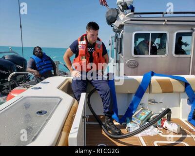 Ein Coast Guard Station Marathon crewmember hilft bei der Entwässerung eines 39-Fuß-Sportboote mit sieben Menschen an Bord Februar 17, 2019 rund 12 Meilen südlich von Vaca Key, Florida. Um ca. 12:20, Key West Coast Guard Sektor watchstanders erhalten einen Notruf über UKW-FM-Radio Kanal 16 von der Crew der Sportboote, Sie nehmen auf Wasser, die aufgefordert, ein Coast Guard Station Marathon 33-Fuß-Special Purpose Handwerk - Strafverfolgung Crew zu starten. Küstenwache Stockfoto
