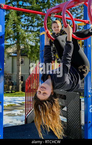 Mädchen kopfüber auf dem Spielplatz bars Stockfoto