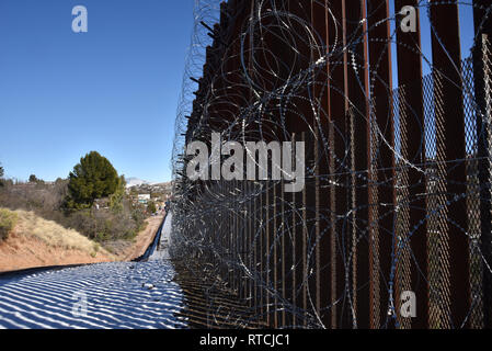 Vier Reihen von Concertina wire decken die Metall Wand in Nogales, Arizona, USA, an der internationalen Grenze zu Nogales, Sonora, Mexiko. Stockfoto