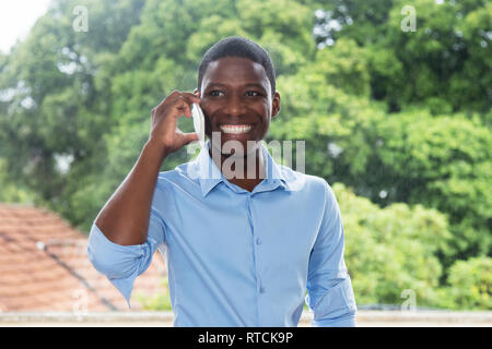 Lachend afrikanischen Geschäftsmann mit Mobiltelefon im Freien in Afrika Stockfoto