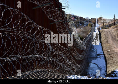 Vier Reihen von Concertina wire decken die Metall Wand in Nogales, Arizona, USA, an der internationalen Grenze zu Nogales, Sonora, Mexiko. Stockfoto