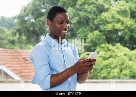 Afrikanische amerikanische Geschäftsmann Sms mit Smartphone im Freien in Afrika Stockfoto
