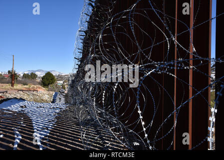 Vier Reihen von Concertina wire decken die Metall Wand in Nogales, Arizona, USA, an der internationalen Grenze zu Nogales, Sonora, Mexiko. Stockfoto