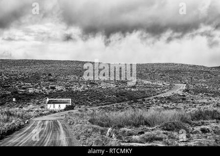 MATJIESRIVIER, SÜDAFRIKA, 27. AUGUST 2018: Landschaft mit einem historischen Haus mit Schilf Dach am Matjiesrivier in der cederberg Mountains. Schwarzweiß Stockfoto