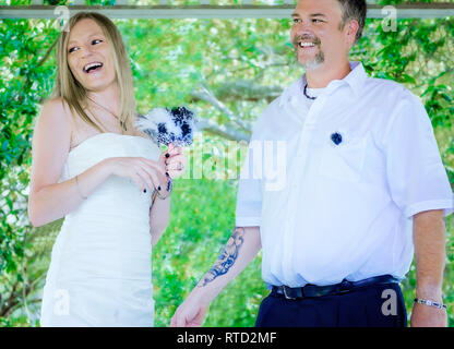 Brautpaar Lachen, während sie nach ihrer Hochzeit Zeremonie am Marschall Park in Ocean Springs, Mississippi sprechen. Stockfoto