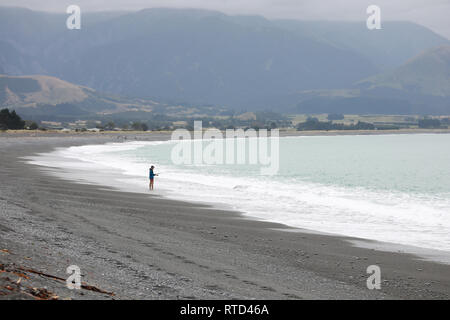 Fischer auf Kaikoura schwarz grau Kieselstrand mit Treibholz Neuseeland Südinsel Stockfoto