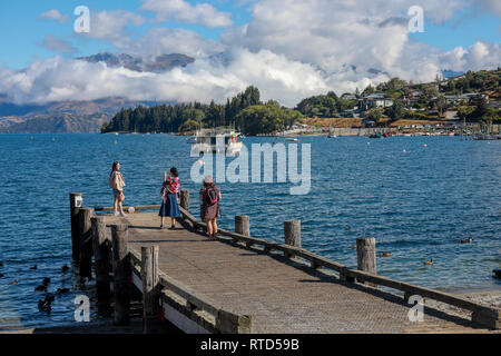 Asiatische und westliche Touristen und einheimische Vögel füttern auf der Pier auf der Sommertag im Sonnenschein Lake Wanaka Neuseeland Südinsel Stockfoto