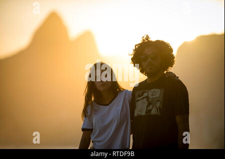 RIO DE JANEIRO - MÄRZ 20, 2017: Ein paar Spaziergänge Vergangenheit ein Sonnenuntergang Silhouette der beiden Brüder Berg entlang der Promenade in Arpoador, Ipanema Strand. Stockfoto