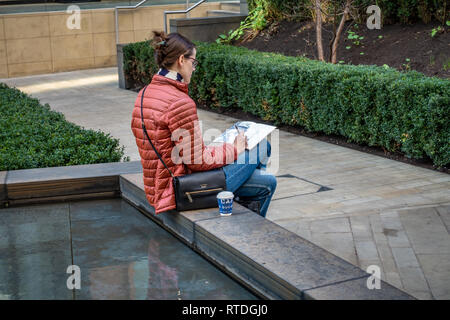 Junge Frau sitzt außerhalb Zeichnung im Innenhof außerhalb von Google UK Corporate Office in Kings Cross, London, England Stockfoto