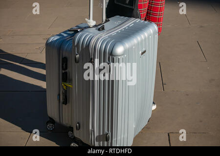 Junge Frau zieht sie zwei manoukian Luggage Set Aluminium Gehäuse aus Kings Cross Bahnhof, London, England Stockfoto