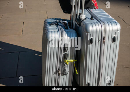 Junge Frau zieht sie zwei manoukian Luggage Set Aluminium Gehäuse aus Kings Cross Bahnhof, London, England Stockfoto