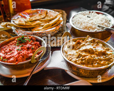 Indisches essen und indische Curry in einem Kupfer Messing serviert orientalische Schale, Hähnchenbrustfilet in Currysauce Zutaten in einen Topf mit der alten Tabelle Stockfoto