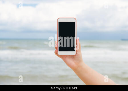 Hand am Meer, mobile Vorlage für Text in der Seite Stockfoto