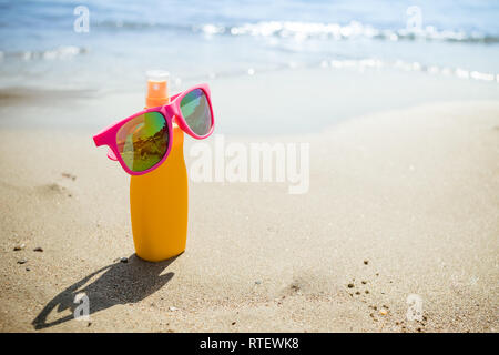 Verschiedene sunsreen Produkte in den Sand. kosmetische Flaschen für die Körperpflege am Strand background.protect Haut vor UV-Strahlen isoliert. Spray Sonnenschutz Stockfoto