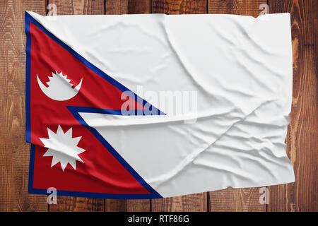 Flagge Nepal auf einem Holztisch Hintergrund. Faltige nepalesische Flagge Ansicht von oben. Stockfoto