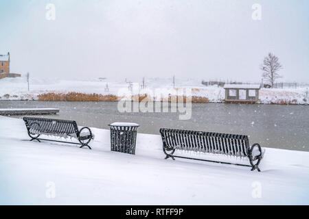 Bänke mit Blick auf einen See an einem Wintertag in Utah. Leere Bänke im Freien auf schneebedeckten Boden im Winter im Morgengrauen, Utah. Die Bänke mit einem Papierkorb Stockfoto