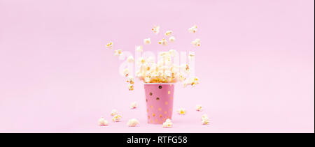 Flying Popcorn in einem hellen Glas und auf einem rosa Hintergrund. Platz kopieren Stockfoto