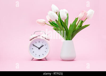 Rosa Wecker und einen Strauß Blumen auf einem rosa Hintergrund Frühling Stockfoto