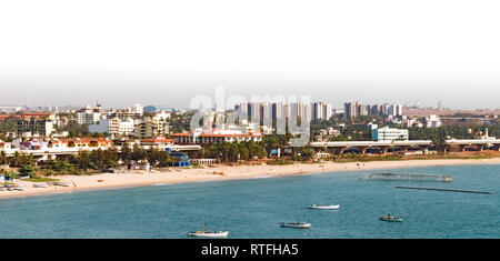 Luftaufnahme der entwickelten Stadt mit Gebäuden, Strandhäuser, Überführung, Palmen, alle entlang der Küste der Ruhe blaues Meer mit verankerten Boote gelegen Stockfoto