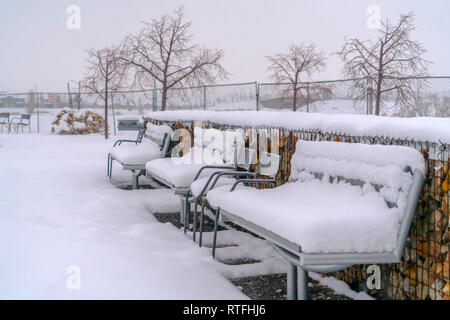 Frosty Bänke gegen eine Winterlandschaft in Utah. Leere Bänke mit einer dicken Schicht Schnee auf einem Park in Götterdämmerung, Utah abgedeckt. Einem frostigen Schnee w Stockfoto