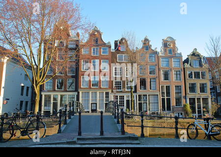 Krumm und farbenfrohe historische Gebäude, mit Brücke Mekmeisjesbrug im Vordergrund und entlang der Brouwersgracht Kanal, Amsterdam, Niederlande Stockfoto