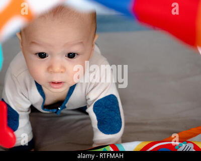 4 Monate alte gemischten Rennen asiatischen Kaukasischen jungen Suchen glücklich lächeln und lachen in die Kamera, gesundes Kind baby boy. Baby beginnt zu kriechen