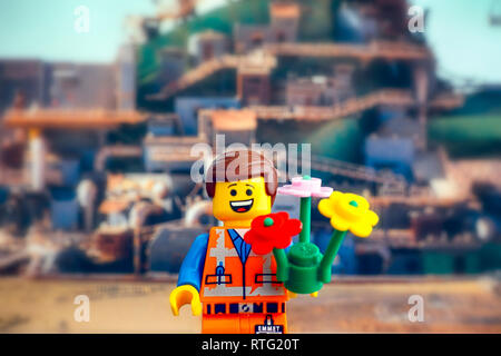 Tambow, Russische Föderation - Februar 24, 2019 Lego harten Hut Emmet Minifigur mit Blumen gegen Apocalypseburg Hintergrund. Die Lego Film 2. Stockfoto