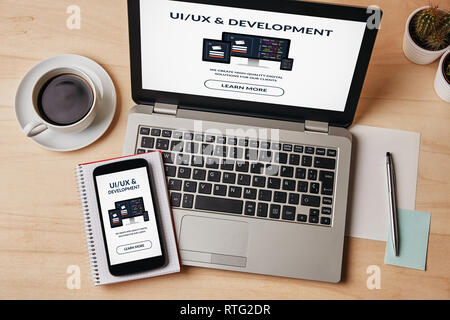UI/UX-Entwurf und Entwicklung Konzept auf Laptop und Smartphone-Bildschirm über die hölzernen Tisch. Alle Inhalte werden von mir gestaltet. Flach Stockfoto