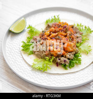 Garnelen Taco mit Kalk auf rundem Schild mit weißem Hintergrund Holz, Seitenansicht. Nahaufnahme. Stockfoto