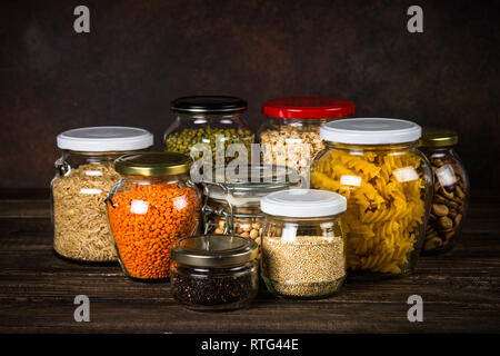 Getreide, Hülsenfrüchte und Bohnen in Gläsern am Küchentisch. Stockfoto