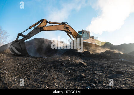 Gelb big Bagger in der Kohlengrube, lasten die Rasse, mit der hellen Sonne und blauen Himmel im Hintergrund. Mining Truck Bergbaumaschinen Stockfoto