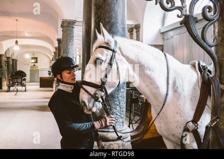 20. Februar 2019. Royal stabil in Dänemark Kopenhagen im Gebiet Christiansborg Slot. Mann junge Frau rider Jockey vorbereiten für ein Zaum, Zaum, oc Stockfoto