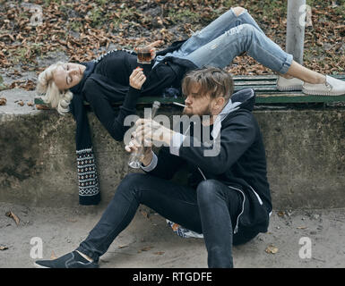 Alco sucht Konzept. Deprimiert und hoffnungslos Paar sitzen, nachdem Sie Alkohol getrunken auf der Straße Stockfoto