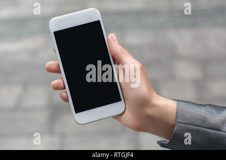 Junge geschäftsfrau stehen auf der Straße mit Bildschirm des Smartphones close-up Stockfoto