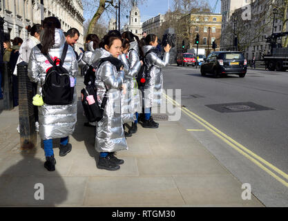 London, England, UK. Gruppe der Besuch der japanischen Schulkinder in identischen Silber Mäntel in Whitehall, Downing Street Stockfoto