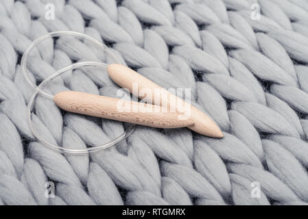 Stricknadeln auf Grau gestrickte Decke aus Merinowolle, super chunky Garn. Stockfoto