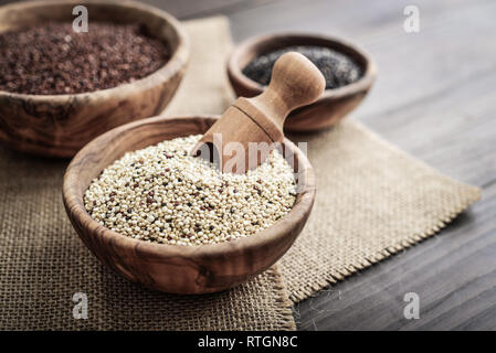 Verschiedene Arten von Raw Quinoa Samen in die hölzerne Schüssel auf Holz- Hintergrund closeup Stockfoto