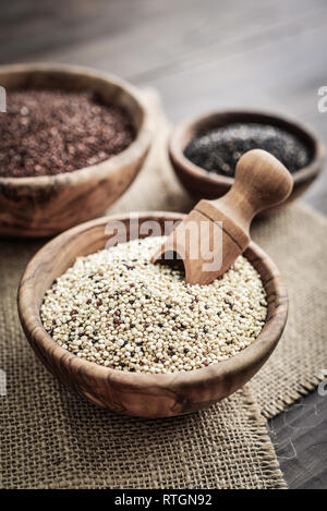 Verschiedene Arten von Raw Quinoa Samen in die hölzerne Schüssel auf Holz- Hintergrund closeup Stockfoto