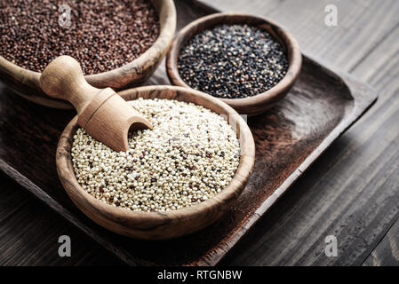 Verschiedene Arten von Raw Quinoa Samen in die hölzerne Schüssel auf Holz- Hintergrund closeup Stockfoto