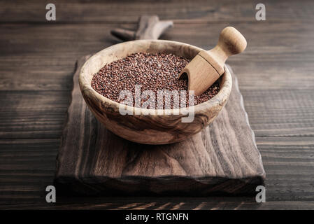 Red Raw Quinoa Samen in die hölzerne Schüssel auf Holz- Hintergrund closeup Stockfoto