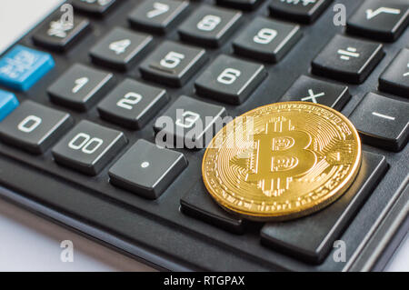 Golden bitcoin Münze auf schwarz Taschenrechner hautnah. Stockfoto
