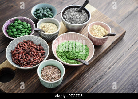 Verschiedene super Foods in Schalen auf einem hölzernen Hintergrund Stockfoto
