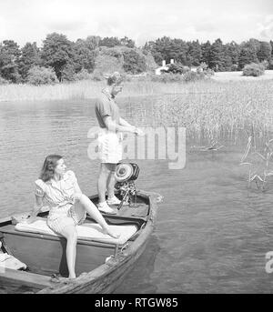 Angeln in den 1940er Jahren. Ein Mann ist das Angeln vom Boot und seine Freundin ist die Sonne genießen, während Sie darauf warten, für ihn einen Fisch zu fangen. Der Außenbordmotor ist vom schwedischen Hersteller Penta gemacht. Auf der ganzen Welt den Namen Penta mit Außenbordmotor in vielen Sprachen synonym wurde. Foto Kristoffersson ref AC 119-5 Schweden 1946 Stockfoto